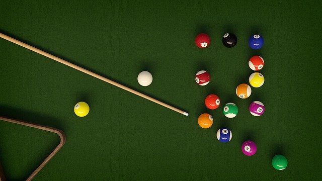 Pool table with billiard balls, cue and triangle ready to be cleaned