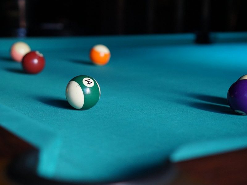 Learn how to clean a pool table for maximum playability represented by a poll table and 6 billird balls