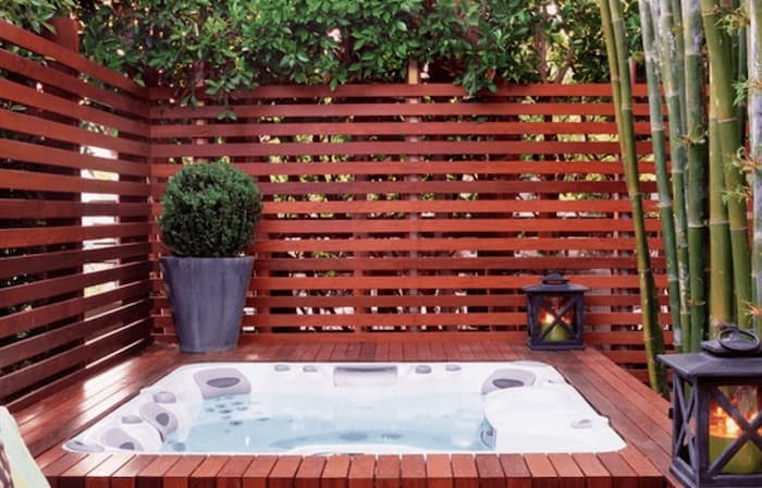 A hot tub with a wooden privacy wall