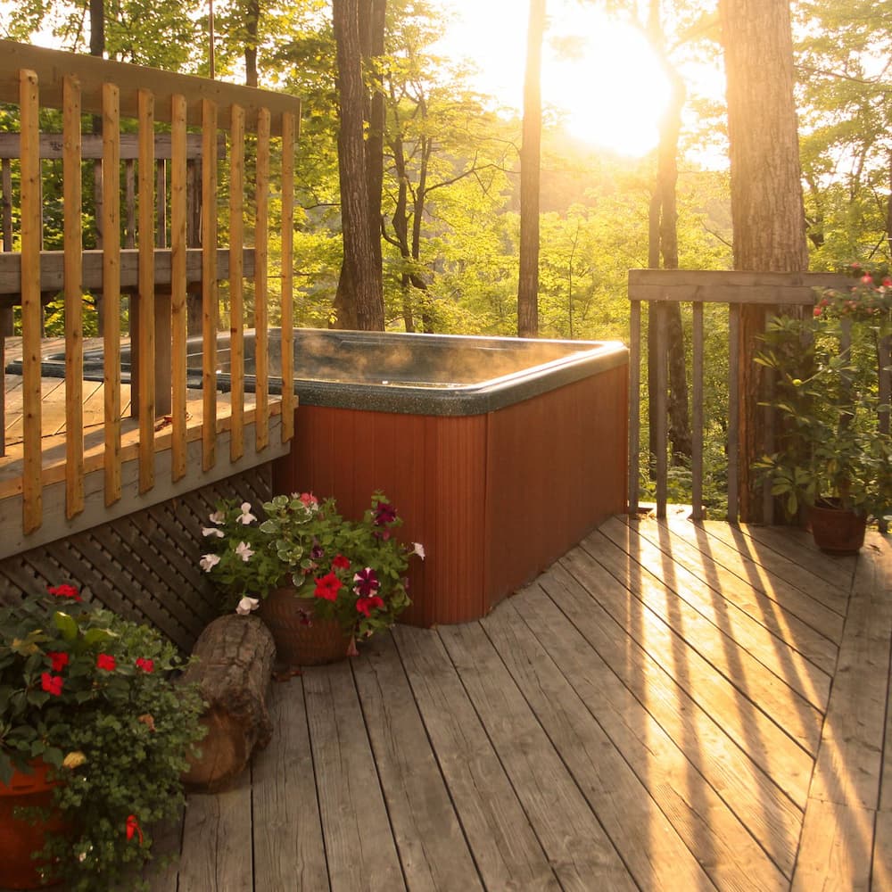 hot tub on the deck with seasonal flowers lined up on the side