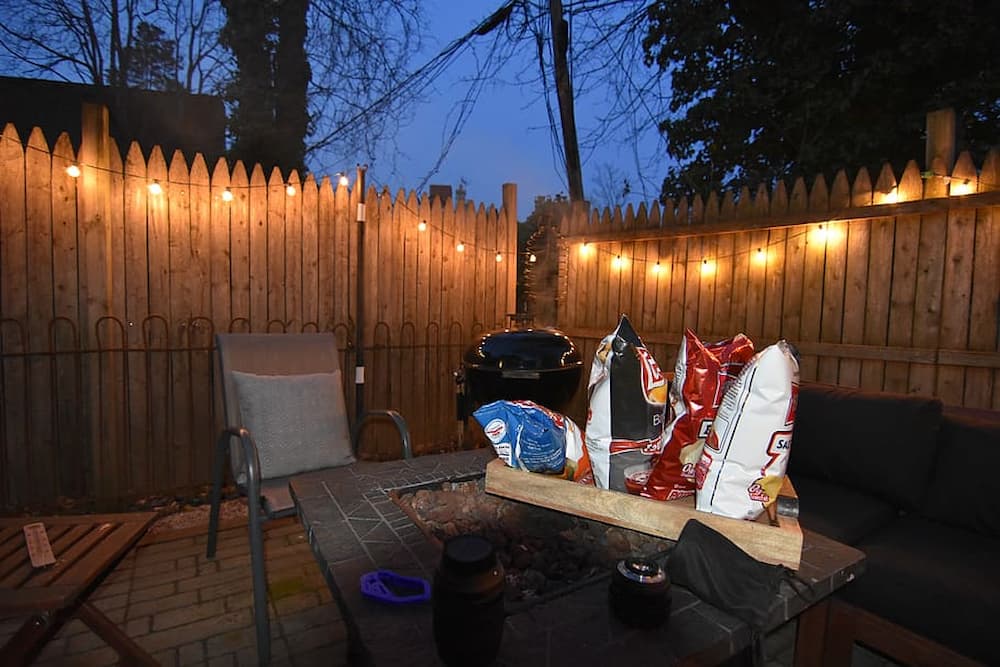 backyard patio table with chips on it and string lights along the fence